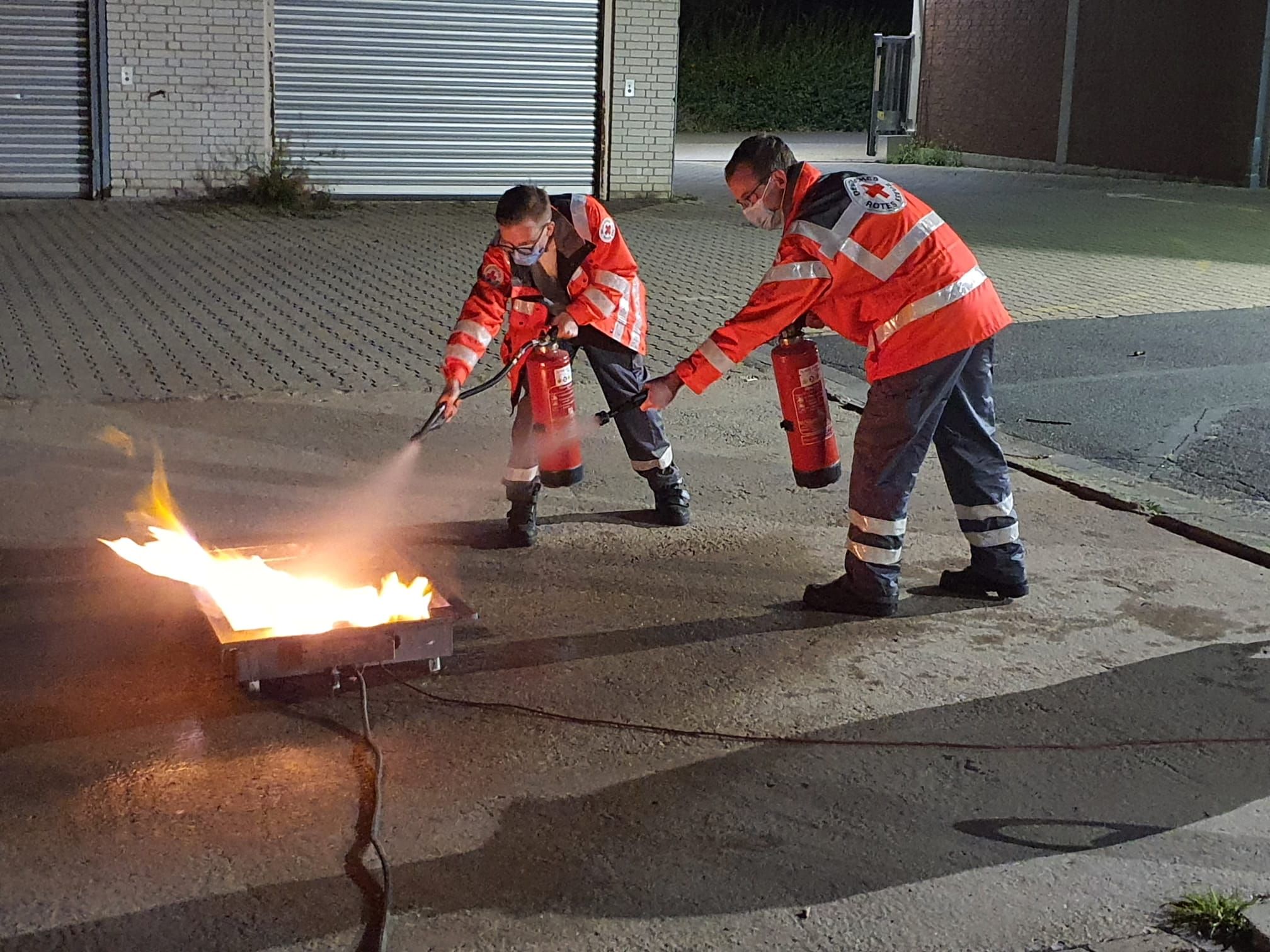 Bild: Zwei DRK-Helfer löschen ein Feuer mit einem Feuerlöscher